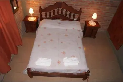 a bed with white sheets and two nightstands and two lamps at Cabañas Raices in Mina Clavero