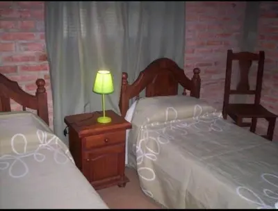 a bedroom with two beds and a lamp on a night stand at Cabañas Raices in Mina Clavero