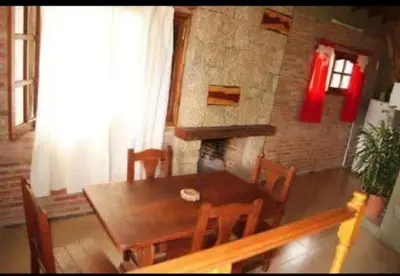 a dining room with a wooden table and a fireplace at Cabañas Raices in Mina Clavero