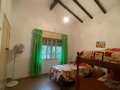 a bedroom with two beds and a window with green curtains at Villa Clara in Villa Parque Siquiman