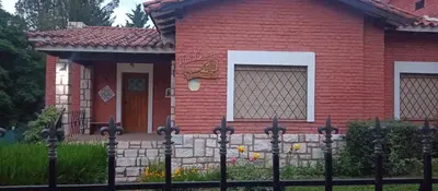a red brick house with a fence in front of it at Villa Clara in Villa Parque Siquiman