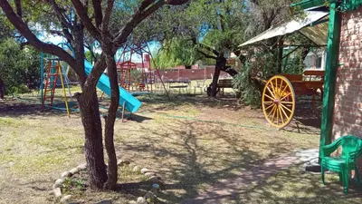 a playground with a yellow wagon and a tree at Valle Hermoso in Mina Clavero