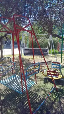 a playground with three swings in a park at Valle Hermoso in Mina Clavero