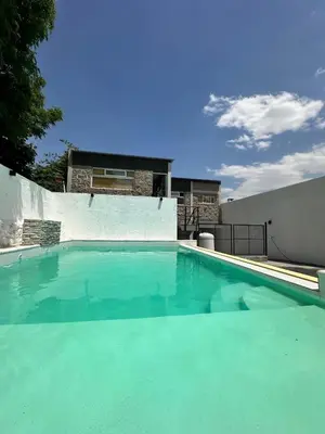 a large swimming pool with green water in front of a house at Valle Hermoso in Mina Clavero