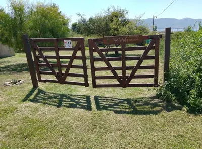 a wooden gate in the grass with a sign on it at Casa WIWI in La Estancia