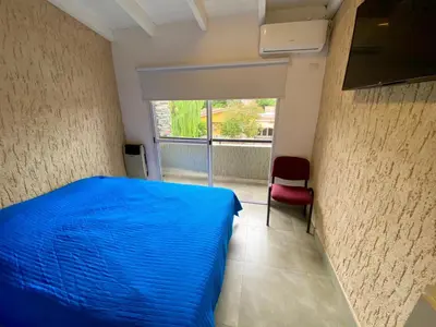 a bedroom with a blue bed and a red chair at Magdalena in Santa Rosa de Calamuchita