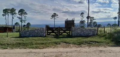 a fence and a stone wall in a field at La Eugelina in Santa Rosa de Calamuchita