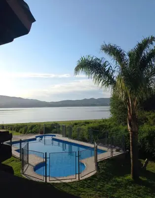 a swimming pool with a palm tree next to the water at Cabaña Ari in Villa Santa Cruz del Lago