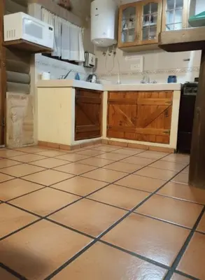 a kitchen with wooden cabinets and a tiled floor at Cabaña Ari in Villa Santa Cruz del Lago