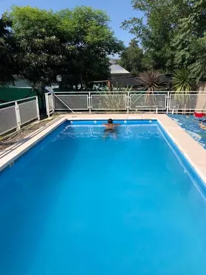 a person swimming in a large blue swimming pool at Apartamentos Dorothy in Villa Santa Cruz del Lago