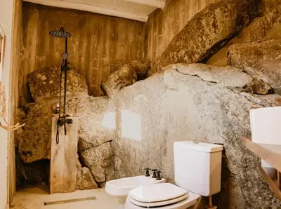 a bathroom with a toilet and a rock wall at Aldea Romerillo in Cavalango
