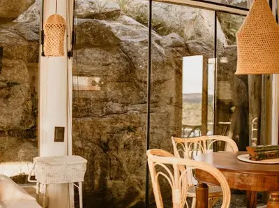 a dining room with a table and chairs and a stone wall at Aldea Romerillo in Cavalango