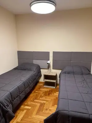 a bedroom with two beds and a lamp in it at Departamento 2 dormitorios in Cordoba