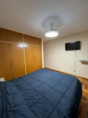 a bedroom with a blue bed and a flat screen tv at Departamento 2 dormitorios in Cordoba