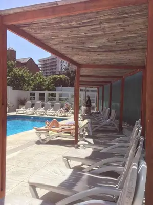 a group of lounge chairs next to a swimming pool at Amérian Carlos Paz Depto Particular 108 in Villa Carlos Paz