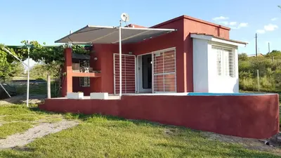a red and white house with an umbrella at Cabaña en Punilla in Villa Parque Siquiman