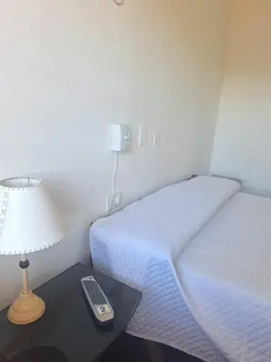 a room with two beds and a table with a lamp at El Redentor in Villa Carlos Paz
