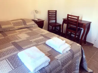 a bedroom with two beds and a table and two chairs at Posta Almendros Apart in Merlo