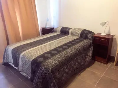 a bedroom with two beds and a table and a lamp at Posta Almendros Apart in Merlo