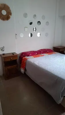 a bedroom with a bed and a nightstand with a clock on the wall at Departamento Temporario - Zona Centro in Cordoba