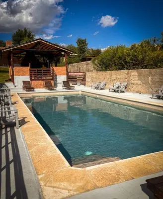 a swimming pool with chairs and a gazebo at Cabañas Altos del Tintero in Mina Clavero
