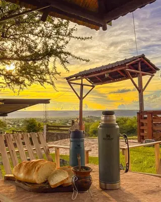 a table with bread and a thermos and a plate of bread at Cabañas Altos del Tintero in Mina Clavero