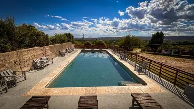 a swimming pool with chairs next to a stone wall at Cabañas Altos del Tintero in Mina Clavero