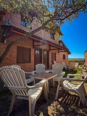 a group of white chairs and a table in front of a house at Cabañas Altos del Tintero in Mina Clavero