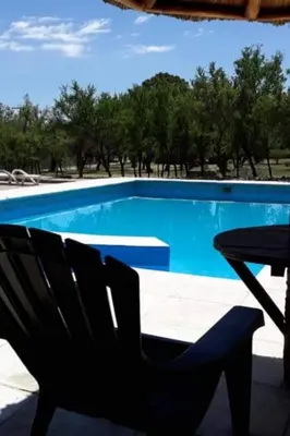 a black chair sitting next to a blue swimming pool at Complejo Entresierras in La Paz