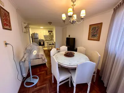 a dining room with a table and white chairs at Departamento Frente al Patio Olmos Shopping in Cordoba