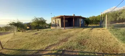 a building with a fence in front of a field at Cabañas Entre Cerros in Merlo