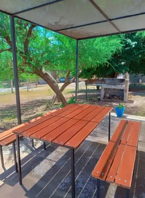a picnic table and a bench under an umbrella at Cabañas Entre Cerros in Merlo