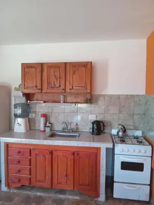 a kitchen with wooden cabinets and a sink and a stove at Cabañas Entre Cerros in Merlo