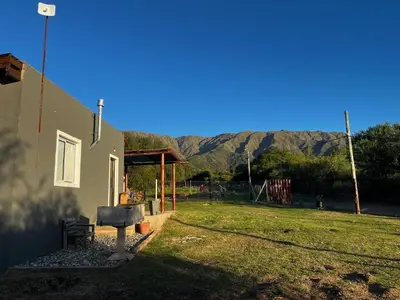 a yard with a house and mountains in the background at Cabañas Entre Cerros in Merlo
