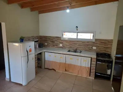 a kitchen with a white refrigerator and a sink at Cabañas Entre Cerros in Merlo