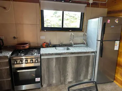 a kitchen with a sink and a stove and a refrigerator at LaJu in Villa Yacanto