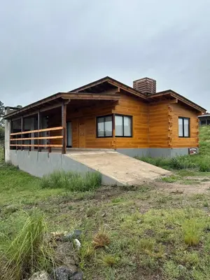 a wooden house with a large driveway in front of it at LaJu in Villa Yacanto