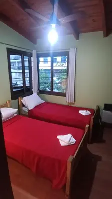 two beds with red sheets in a room with windows at Moderno y acogedor Depto Céntrico V Carlos Paz 200 m terminal Sobre Av San Martin in Villa Carlos Paz