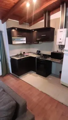 a kitchen with a stove and a couch in a room at Moderno y acogedor Depto Céntrico V Carlos Paz 200 m terminal Sobre Av San Martin in Villa Carlos Paz