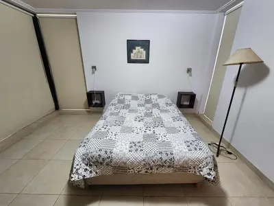 a bedroom with a bed with a black and white comforter at Lago los Molinos Punto Claro villa Silvestre depto 2 dorm y cochera in Villa Ciudad Parque