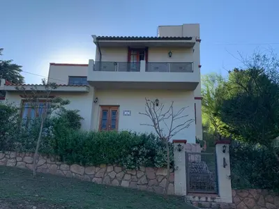 a white house with a stone retaining wall at Hermosa casa de veraneo con pileta in Villa Carlos Paz