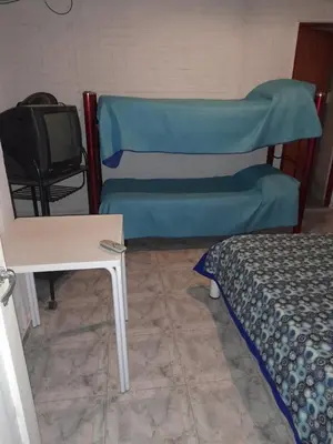 a room with a bed and a table and a tv at Alojamiento Nonino in Villa Cura Brochero