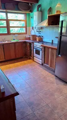 a kitchen with wooden cabinets and a tile floor at Chalet Tala Huasi, Costa Rio, Pileta in Villa Icho Cruz
