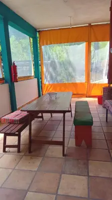 a wooden table and benches in a room with windows at Chalet Tala Huasi, Costa Rio, Pileta in Villa Icho Cruz