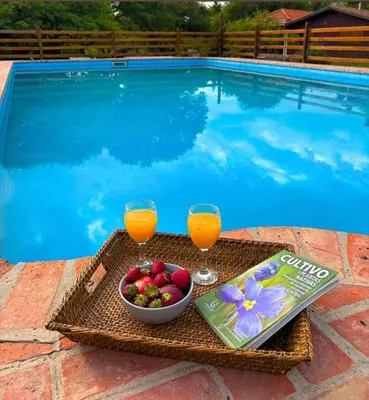 a tray of fruit and drinks next to a swimming pool at La Almenara Lodge in Villa General Belgrano