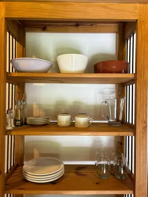 a wooden shelf with plates and bowls and glasses at La Almenara Lodge in Villa General Belgrano