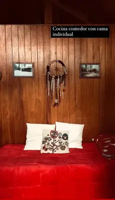 a bedroom with a red bed with wooden walls at Cabañas Lothlorien in Villa Yacanto