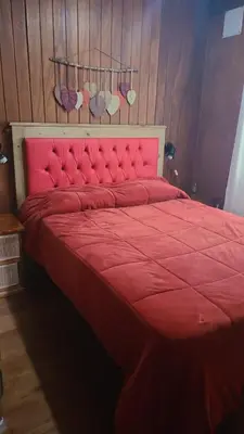 a red bed with a red comforter and someothsternessternessternessterness at Cabañas Lothlorien in Villa Yacanto