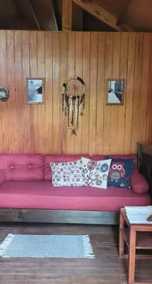 a pink couch in a room with a wooden wall at Cabañas Lothlorien in Villa Yacanto