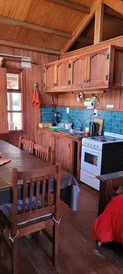 a kitchen with wooden cabinets and a table and a stove at Cabañas Lothlorien in Villa Yacanto